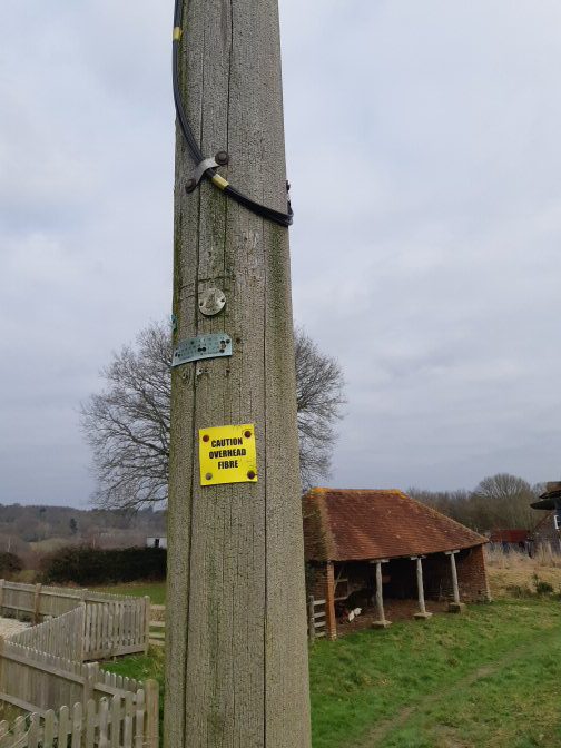 Telegraph pole with "fibre overhead" warning label
